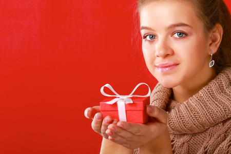 A young woman is standing while holding a bag of gifts over her shoulder .の写真素材