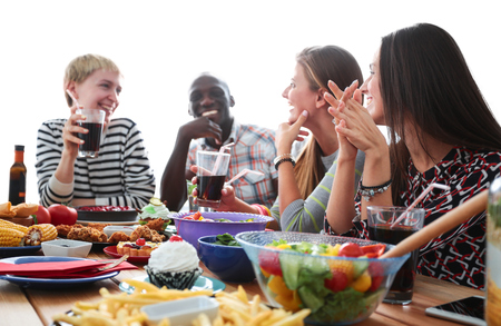 Group of people having dinner together while sitting at wooden table.の写真素材