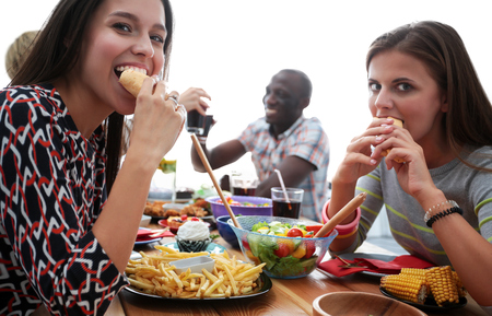 Group of people having dinner together while sitting at wooden table.の写真素材
