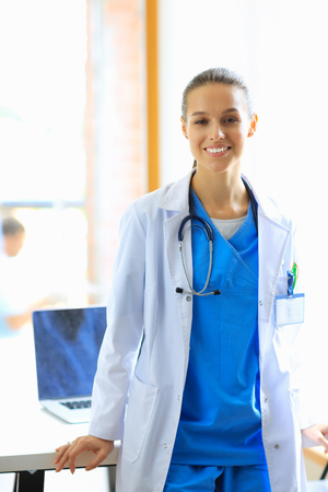 Woman doctor standing at hospital near desk.の写真素材