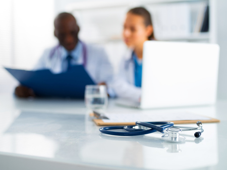 Stethoscope on the desk and young medical people as background.の写真素材