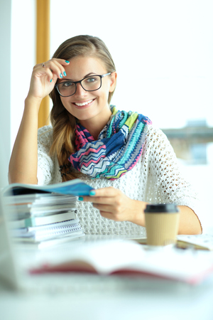 Young woman sitting at a desk among books.の写真素材
