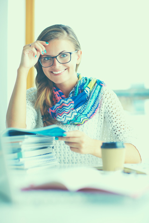 Young woman sitting at a desk among books.の写真素材