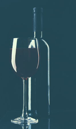 A glass of wine and a bottle on black background.の写真素材