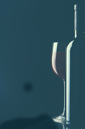 A glass of wine and a bottle on black background.の写真素材