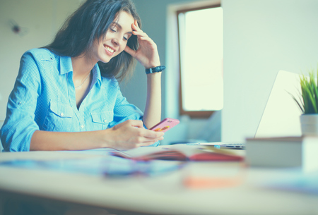 Young woman sitting at office table with laptop.の写真素材