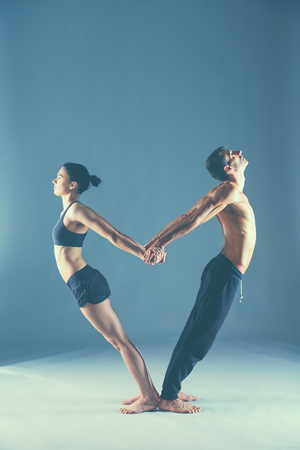 Young couple practicing acro yoga on mat in studio together.の写真素材