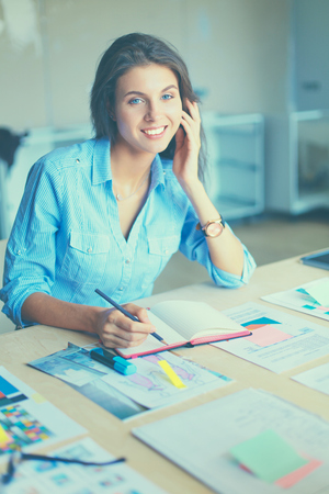 Young woman sitting at the desk with instruments, plan and laptop.の写真素材