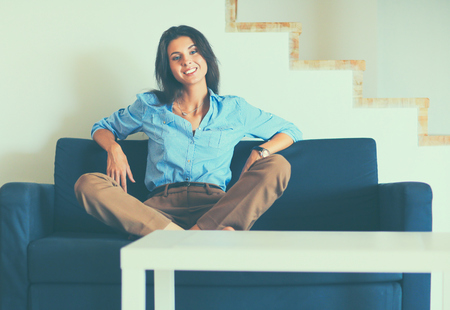 Portrait of happy young woman sitting on sofa.の写真素材