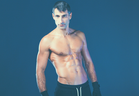 Strong athletic man standing on black background.の写真素材