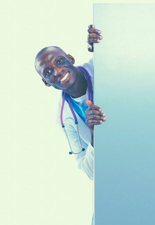Male doctor holding empty placard standing on white background.の写真素材