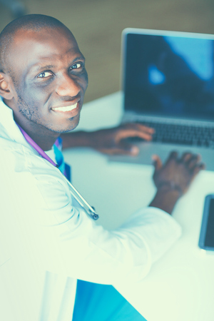 Young african doctor working on laptop at desk.の写真素材