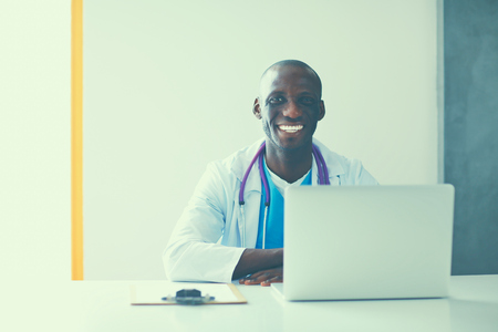 Young african doctor working on laptop at desk.の写真素材