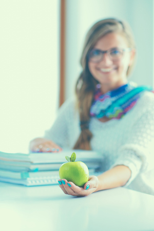 Female college students sitting on the desk with apple a pile of books.の写真素材