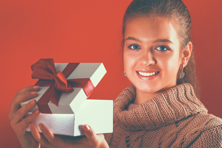 A young woman is standing while holding a bag of gifts over her shoulder .の写真素材