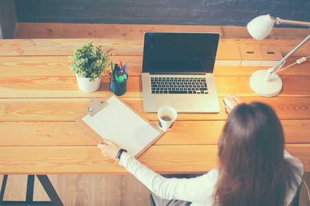Portrait of relaxed young woman sitting at her desk holding cup of coffeeの写真素材