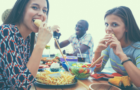 Group of people having dinner together while sitting at wooden table.の写真素材