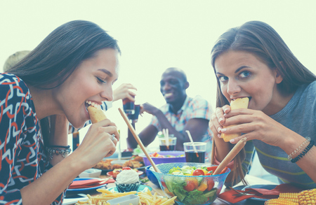 Group of people having dinner together while sitting at wooden table.の写真素材