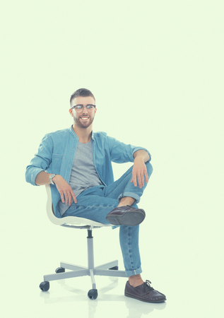 Young man sitting on the chair isolated over white background.の写真素材