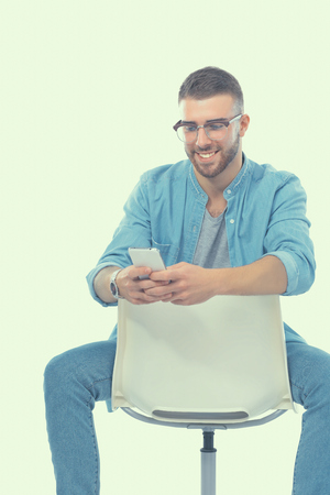 Young man sitting on chair and using mobile phone.の写真素材