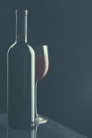 Glass of wine and a bottle on black background.の写真素材
