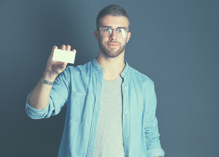 Man holding a credit card, isolated on black background.の写真素材