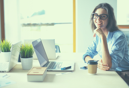 Young woman sitting at office table with laptop.の写真素材
