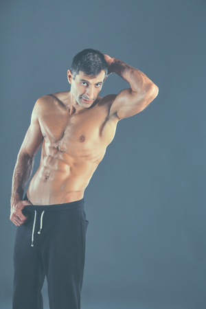 Strong athletic man standing on black background.の写真素材