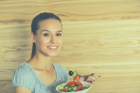 A beautiful girl eating healthy food on wooden backgroundの写真素材