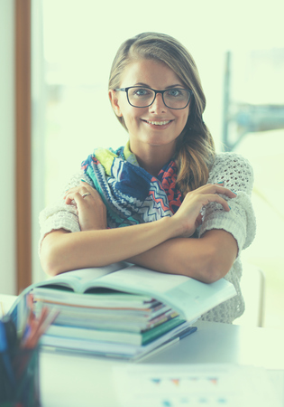 Young woman sitting at a desk among books.の写真素材