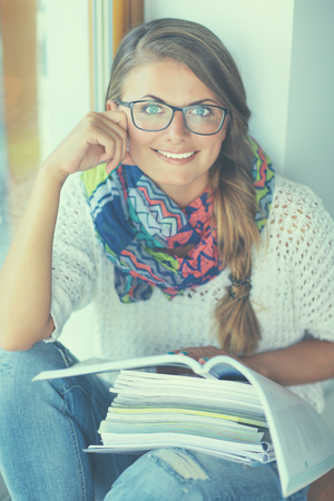 Happy student girl sitting with pile of books.の写真素材