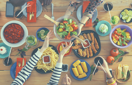 Top view of group of people having dinner together while sitting at wooden tableの写真素材