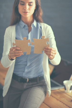Business woman holding and pointing to a puzzle piece.の写真素材