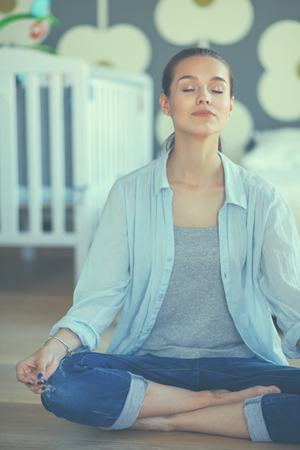 Young woman doing yoga at home in the lotus position.の写真素材
