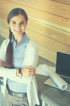 Young female standing near desk with laptop.の写真素材