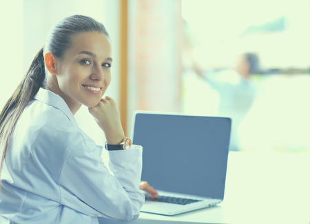 Beautiful young smiling female doctor sitting at the desk.の写真素材