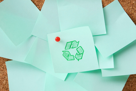 Green recycle sign on green paper isolated on board background.の写真素材