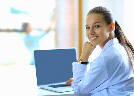Beautiful young smiling female doctor sitting at the deskの写真素材