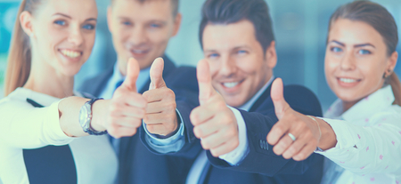 Happy business team showing thumbs up in officeの写真素材