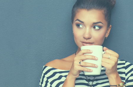 Portrait of young woman with cup tea or coffeeの写真素材