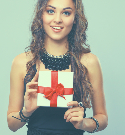 Young woman happy smile hold gift box in hands, isolated over gray backgroundの写真素材