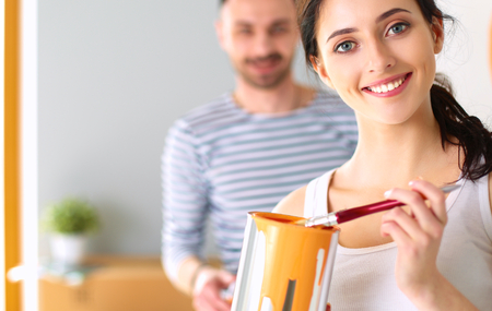 Portrait happy smiling young couple painting interior wall of new houseの写真素材