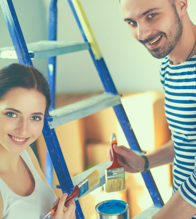 Portrait happy smiling young couple painting interior wall of new houseの写真素材