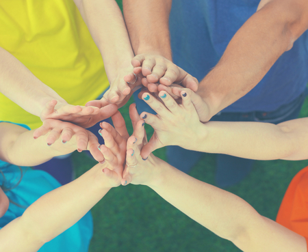 Many arms holding hands together above green grassの写真素材