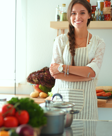 Young woman standing near desk in the kitchenの写真素材
