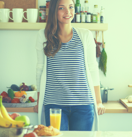 Young woman standing near desk in the kitchenの写真素材