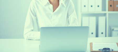 Young woman sitting at office table with laptopの写真素材