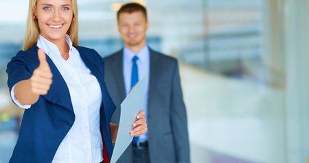 Successful young businesswoman showing ok , standing in officeの写真素材