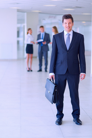 Portrait of young businessman in office with colleagues in the backgroundの写真素材