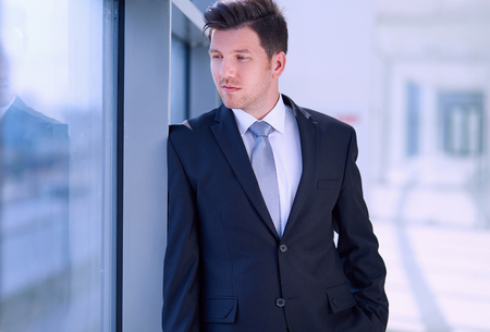 Portrait of businessman standing near window in officeの写真素材